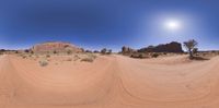 a 360 - vision view of dirt road winding through the desert with a sunny sky