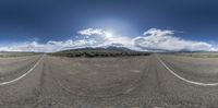 this is a panoramic image of a road and mountains on either side of the roadway