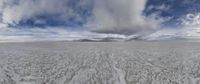 an empty beach on a sunny day under blue clouds and white clouds and mountains with trees in the background