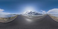 a 360 - fish eye view of a road leading out into the distance through a mountain range