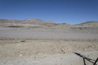 a dirt road is surrounded by some hills and desert like terrain as the vehicle sits on it