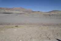 a dirt road is surrounded by some hills and desert like terrain as the vehicle sits on it