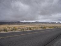 a lone road on a deserted plain near a desert plain with two yellow lines on the side