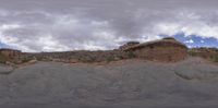 a large sandy surface sits against a cloudy sky while a few large rocks surround it