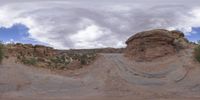 a panoramic view of a wide desert area with rocks, plants and dirt