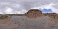 a panoramic view of a wide desert area with rocks, plants and dirt