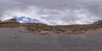 a panoramic view of a wide desert area with rocks, plants and dirt