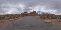 a panoramic view of a wide desert area with rocks, plants and dirt