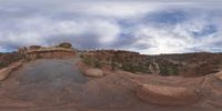 a panoramic view of a wide desert area with rocks, plants and dirt