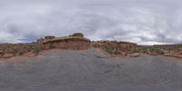 a panoramic view of a wide desert area with rocks, plants and dirt