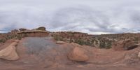 a panoramic view of a wide desert area with rocks, plants and dirt