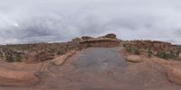 a panoramic view of a wide desert area with rocks, plants and dirt