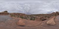 a panoramic view of a wide desert area with rocks, plants and dirt