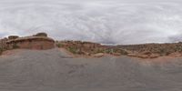 a panoramic view of a wide desert area with rocks, plants and dirt