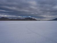 this photo shows the vast view of a salt flats plain with mountains in the distance