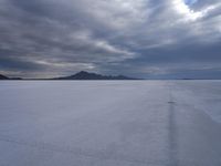 this photo shows the vast view of a salt flats plain with mountains in the distance