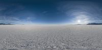 a wide angle view of the vast snow field with the sun peeking through the clouds