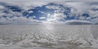 a surreal photo of a large open field in snow with white clouds and a blue sky