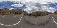 360 - ball image of a paved road passing between cliffs and grass field with clouds