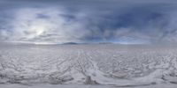 a view of a vast frozen plain from the side of a ski slope while clouds roll over