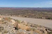 a road with a mountain view in the distance, and large rocks are on the road