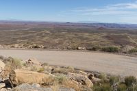 a road with a mountain view in the distance, and large rocks are on the road