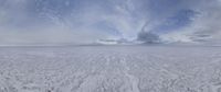 a white snowy landscape on a cloudy day with clouds above it and the sky in the center