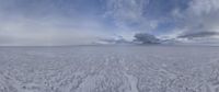 a white snowy landscape on a cloudy day with clouds above it and the sky in the center