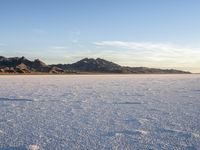 a man walking on the snow with no shoes and mountains in the background in the distance