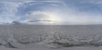 snow covered field with sky and clouds in background, and snow - like snowbank