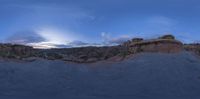 a group of rock formations at sunset in a desert with blue skies and clouds overhead