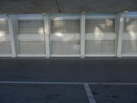 a view of a bench and several windows from inside a building, a red fire hydrant sitting beside it