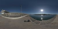 a 360 - view image of the beach, sun and a building and pier area