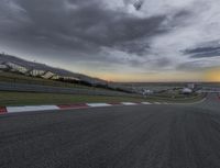 a race track with a cloudy sky in the background and a sunset in the foreground