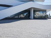 a concrete stairway leading to a white building with glass railings on the outside of it