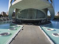 a modern building in spain with large, curved windows on the facade and walkway below