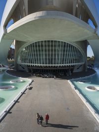 a modern building in spain with large, curved windows on the facade and walkway below