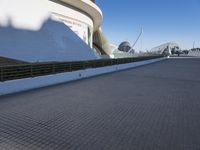 a walkway surrounded by concrete cone poles near a museum and buildings near the sea side