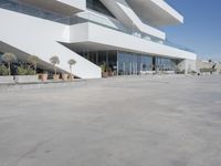 a long, concrete courtyard in front of some modern buildings on the edge of a beach