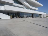 a long, concrete courtyard in front of some modern buildings on the edge of a beach