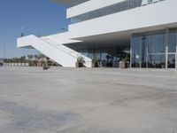 a long, concrete courtyard in front of some modern buildings on the edge of a beach