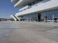 a long, concrete courtyard in front of some modern buildings on the edge of a beach