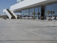 a long, concrete courtyard in front of some modern buildings on the edge of a beach