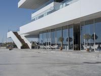 a long, concrete courtyard in front of some modern buildings on the edge of a beach