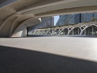 a walkway with curved arches in front of modern buildings, near a street and sidewalk