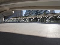 a walkway with curved arches in front of modern buildings, near a street and sidewalk
