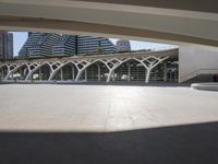 a walkway with curved arches in front of modern buildings, near a street and sidewalk