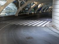 a long, curved walkway with concrete walls on either side of it is empty and the train is coming up