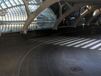 a long, curved walkway with concrete walls on either side of it is empty and the train is coming up