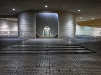 the outside of an empty building at night with a large lit doorway in the middle of the hallway